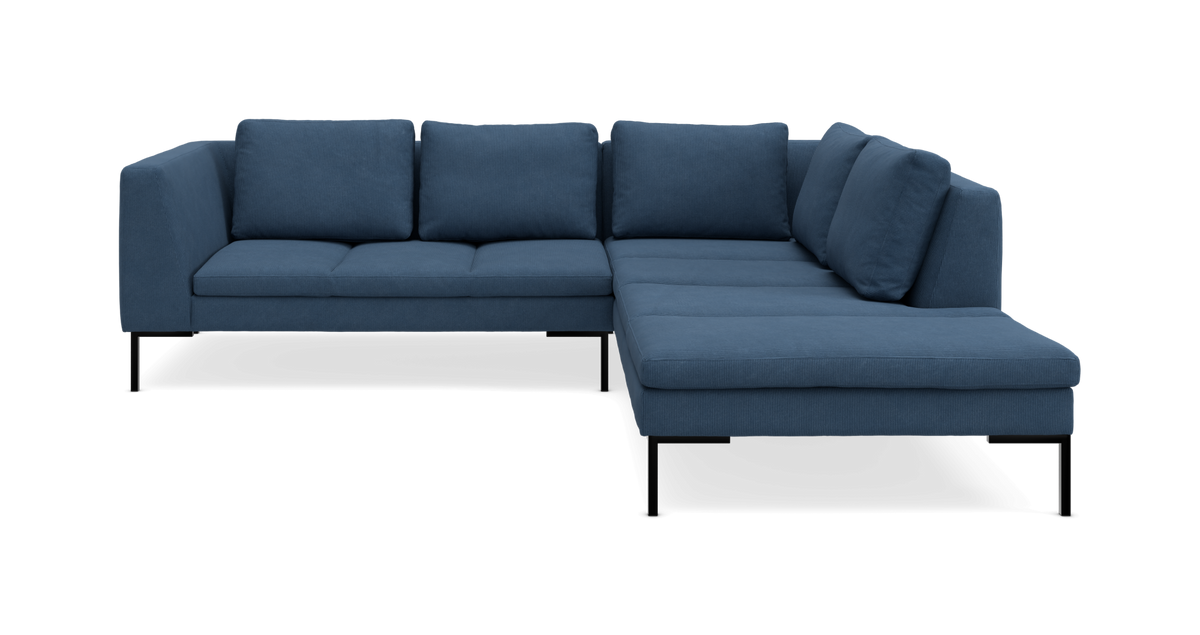 Blå L-formet hjørnesofa med chaiselong til højre på slanke sorte ben.