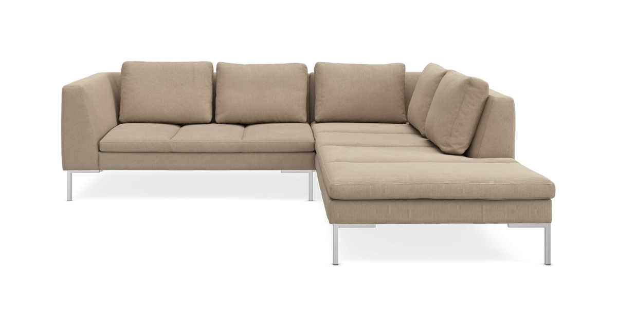 Beige L‑sofa i stof med chaiselong til højre og slanke metalben, frilagt på hvid baggrund.