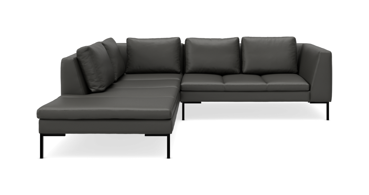 Mørkegrå L‑sofa med chaiselong til venstre, fire ryghynder og slanke sorte ben.