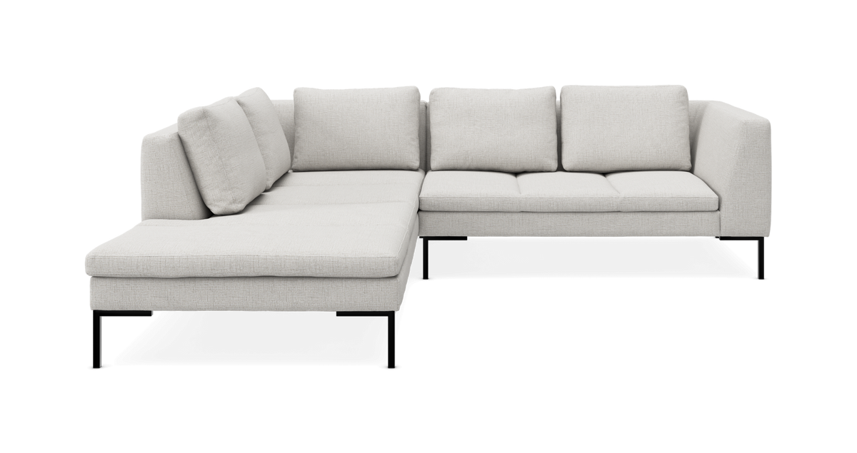 L‑formet modulsofa i lysegråt stof med slanke sorte ben, frilagt på hvid baggrund.