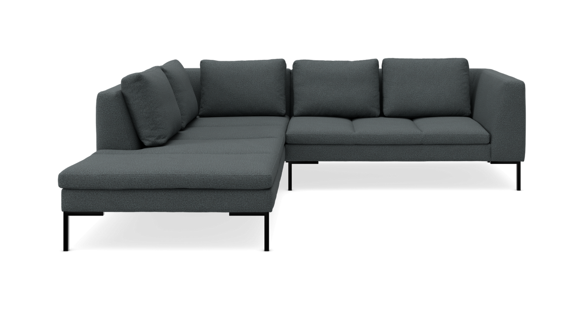 Mørkegrå L-formet hjørnesofa med chaiselong til venstre, slanke sorte ben og løse ryghynder, frilagt mod neutral baggrund.