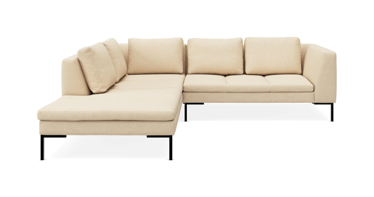 Beige hjørnesofa med chaiselong til venstre, sorte metalben og løse ryghynder, frilagt på hvid baggrund.
