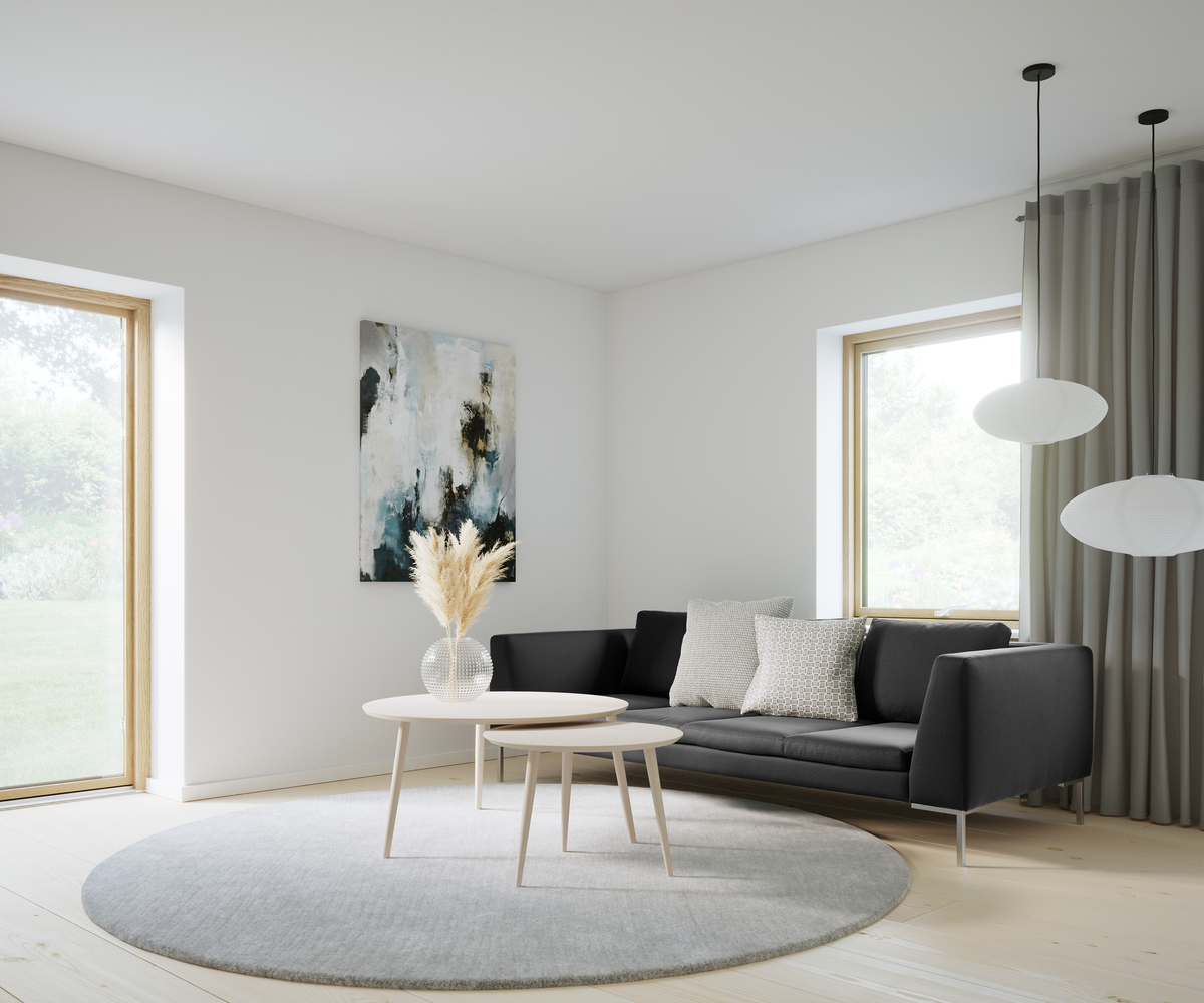 Lyst stue med sort sofa, lyse runde sofaborde, gråt rundt tæppe, abstrakt vægkunst og hvide rislamper ved store vinduer.