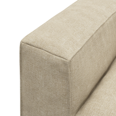 Nærbillede af beige sofa-armlæn i stof i studiemiljø.