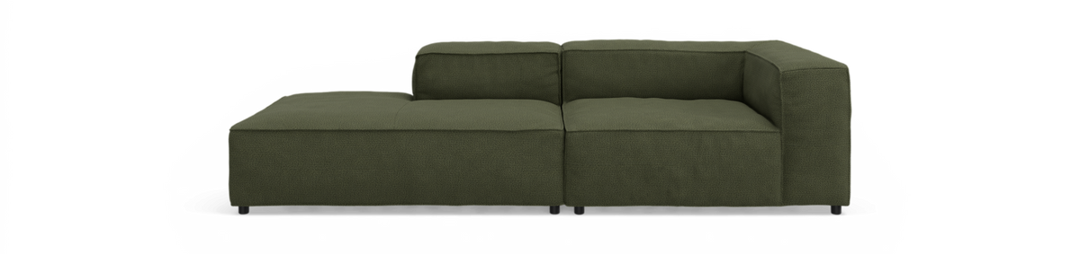 Mørkegrøn modulsofa med chaiselong til venstre, set direkte forfra mod sort baggrund.