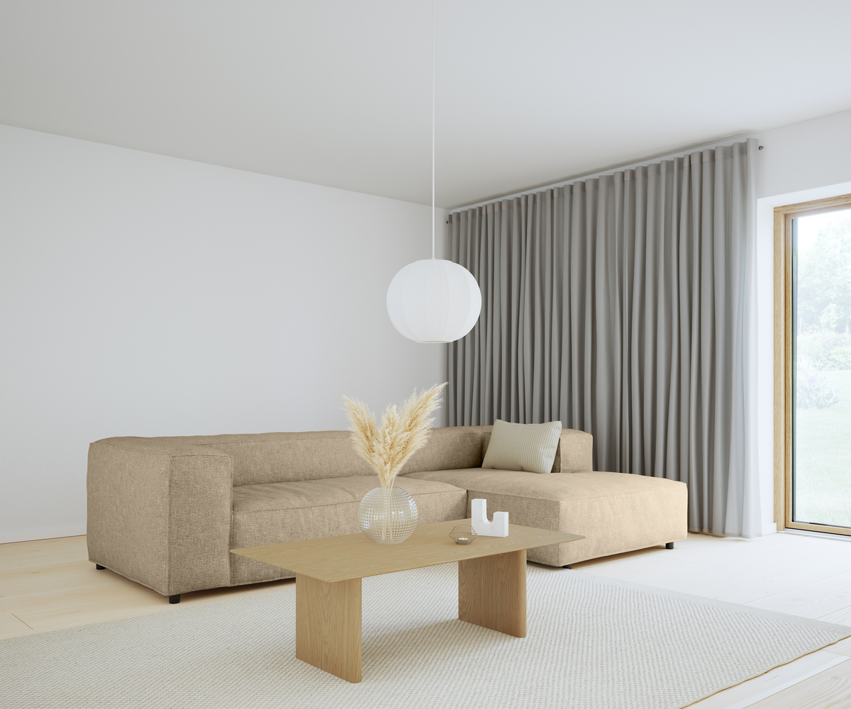 Lys skandinavisk stue med beige hjørnesofa, træbord, rund hvid pendellampe og grå gardiner ved stort vindue.