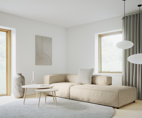Lyst stue i skandinavisk stil med beige modulsofa, to runde hvide sofaborde, stor keramikvase, rundt gråt tæppe, vægkunst, gardiner og to hængende rislamper ved vinduet i dagslys.