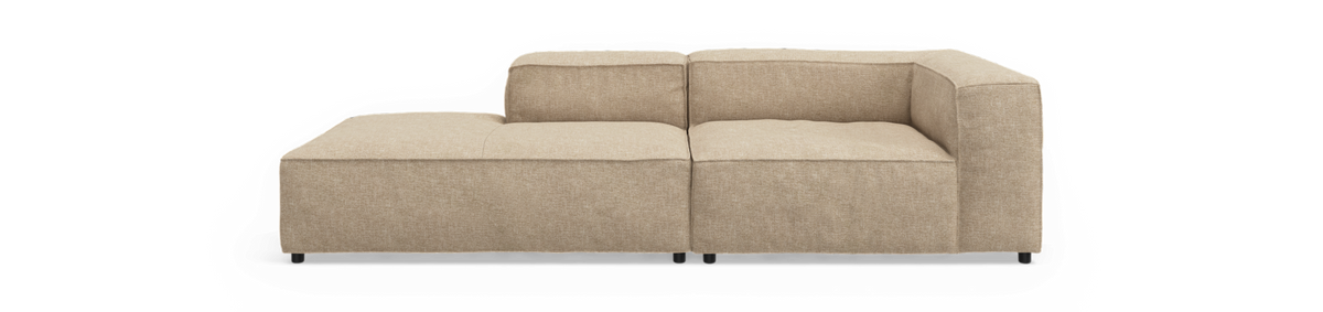 Beige modulsofa med venstre chaiselong, lav ryg og kubisk design, frilagt i studiovisning.