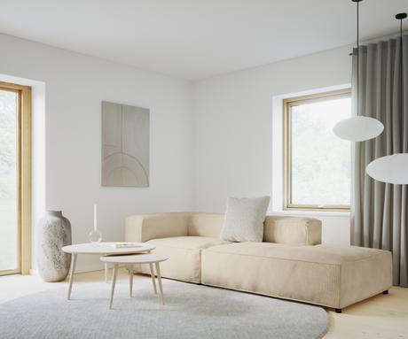 Lyst stue med beige modulsofa, to runde sofaborde, rundt gråt tæppe, stor keramikvase, vægkunst og hvide pendler ved vinduer med gardiner – minimalistisk skandinavisk stil.