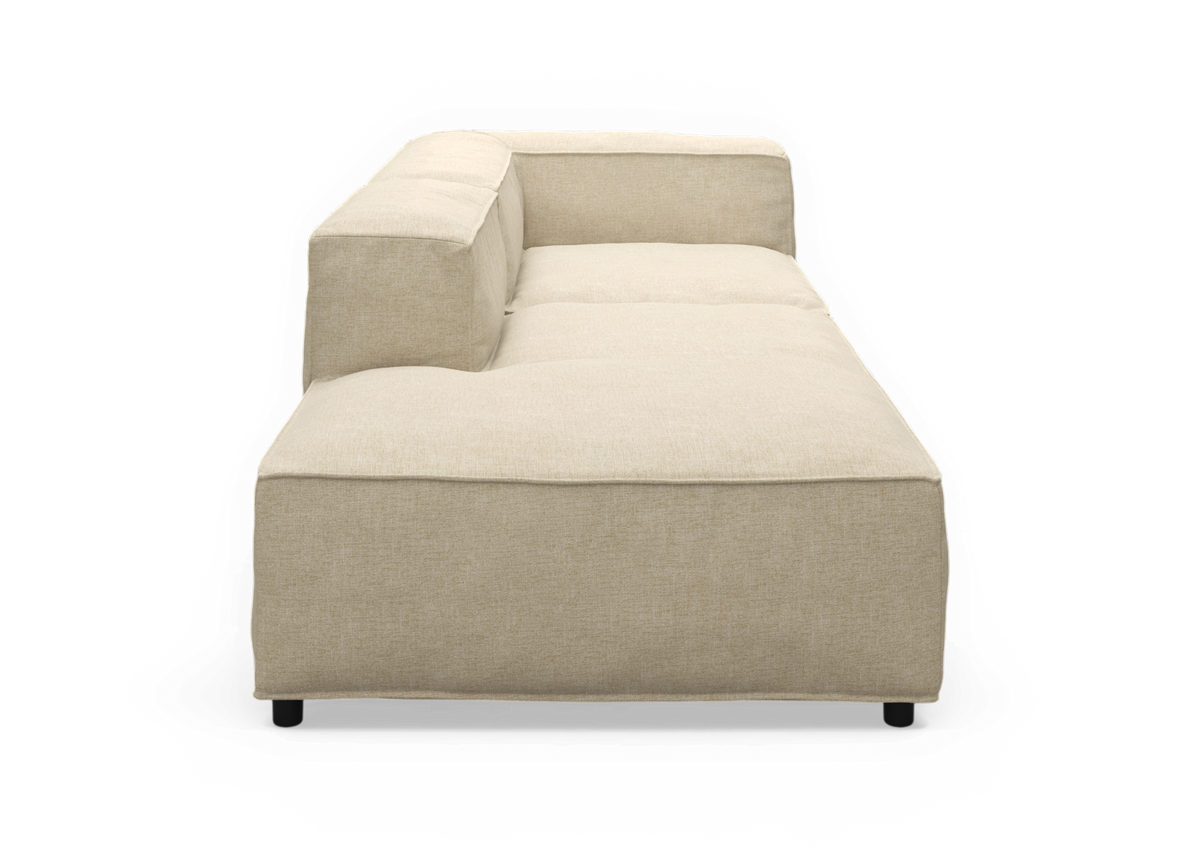 Beige modulsofa med venstre chaiselong set fra siden, frilagt på sort baggrund.