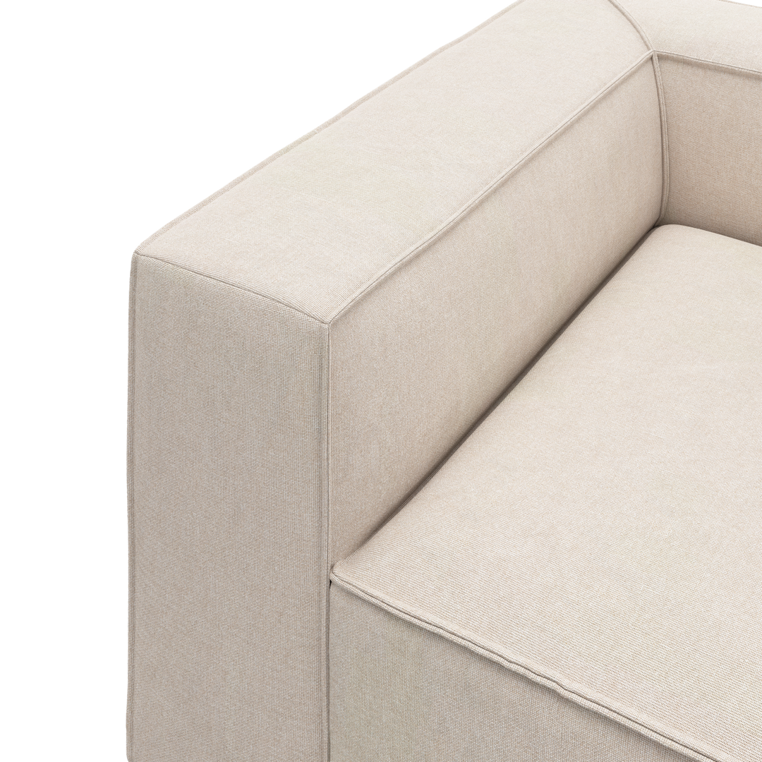 Nærbillede af beige sofa-hjørne med bred armlæn og sædepude i stof på hvid baggrund.