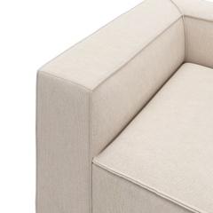 Nærbillede af beige sofa-hjørne med bred armlæn og sædepude i stof på hvid baggrund.