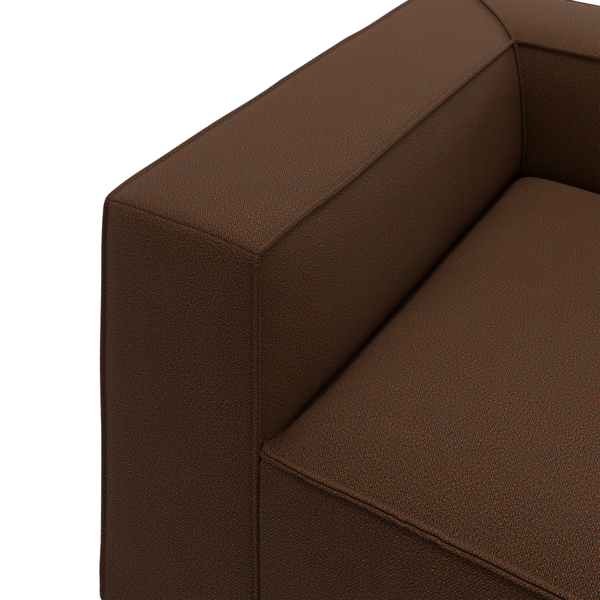 Nærbillede af brun stofsofa med boxet armlæn og sæde i moderne, ren stil.