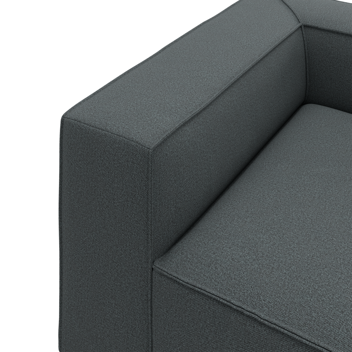 Nærbillede af mørkegrå stofsofa med firkantet armlæn og sæde i moderne, stramt design.