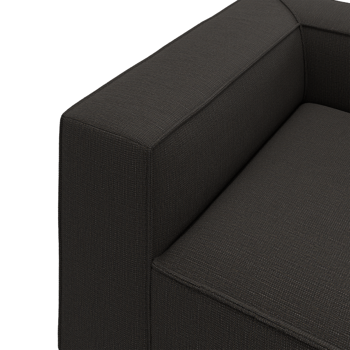 Nærbillede af mørkegrå stofsofa – armlæn og sæde i stramt, moderne design.