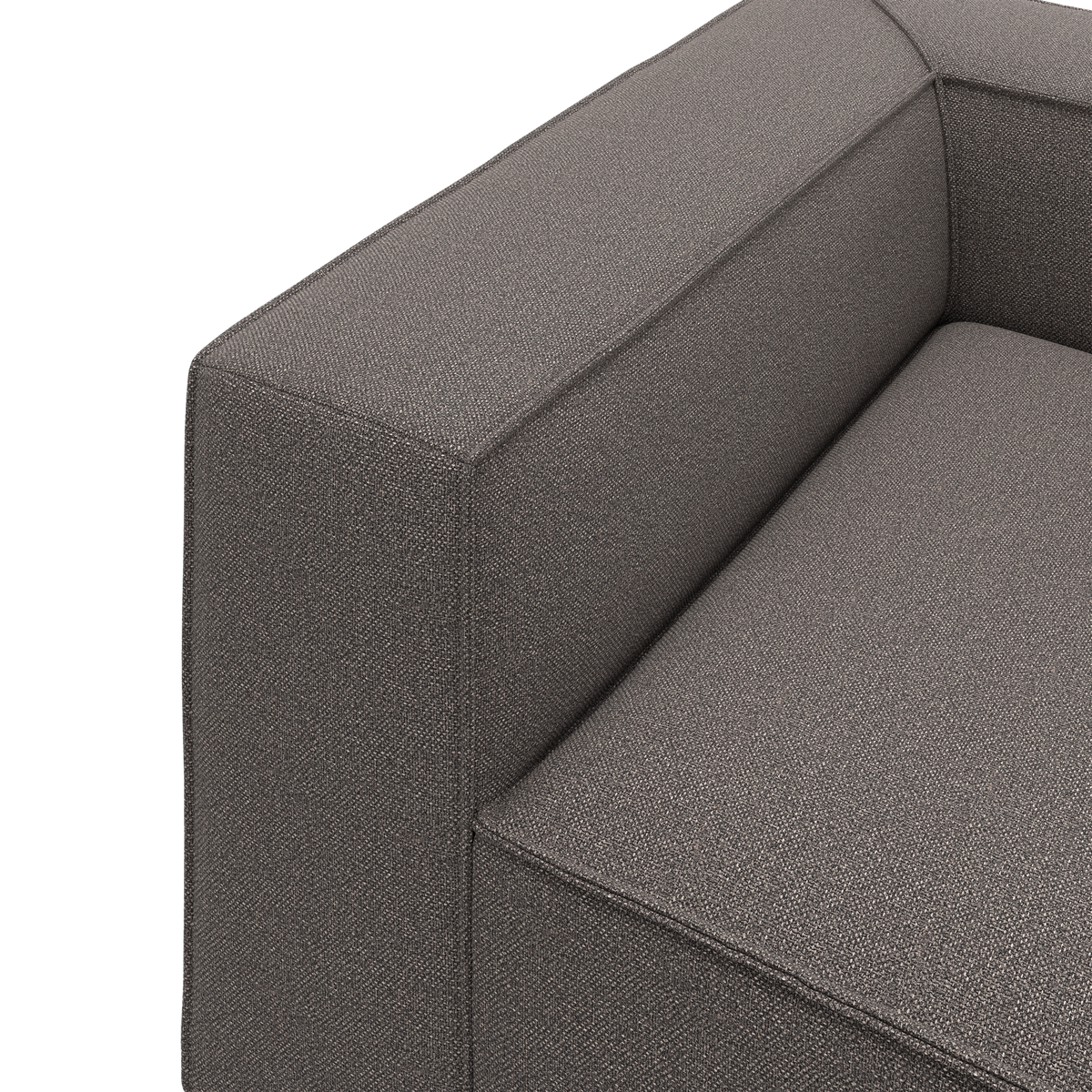Nærbillede af en grå stofsofa med firkantet armlæn og sæde i moderne, boxet design.