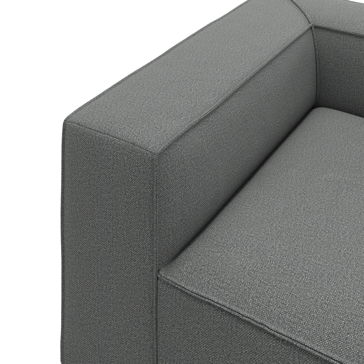 Nærbillede af en grå stofbetrukket sofa med kantet armlæn og sæde i moderne stil.