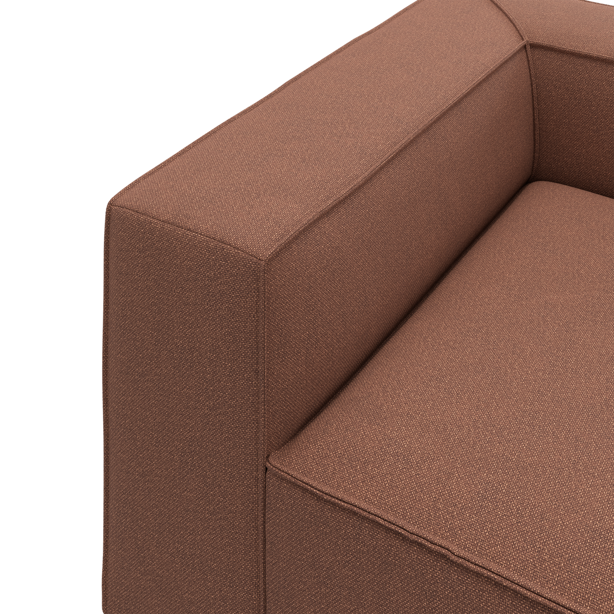 Close-up af brun stofsofa med tydeligt armlæn og sæde i minimalistisk stil.