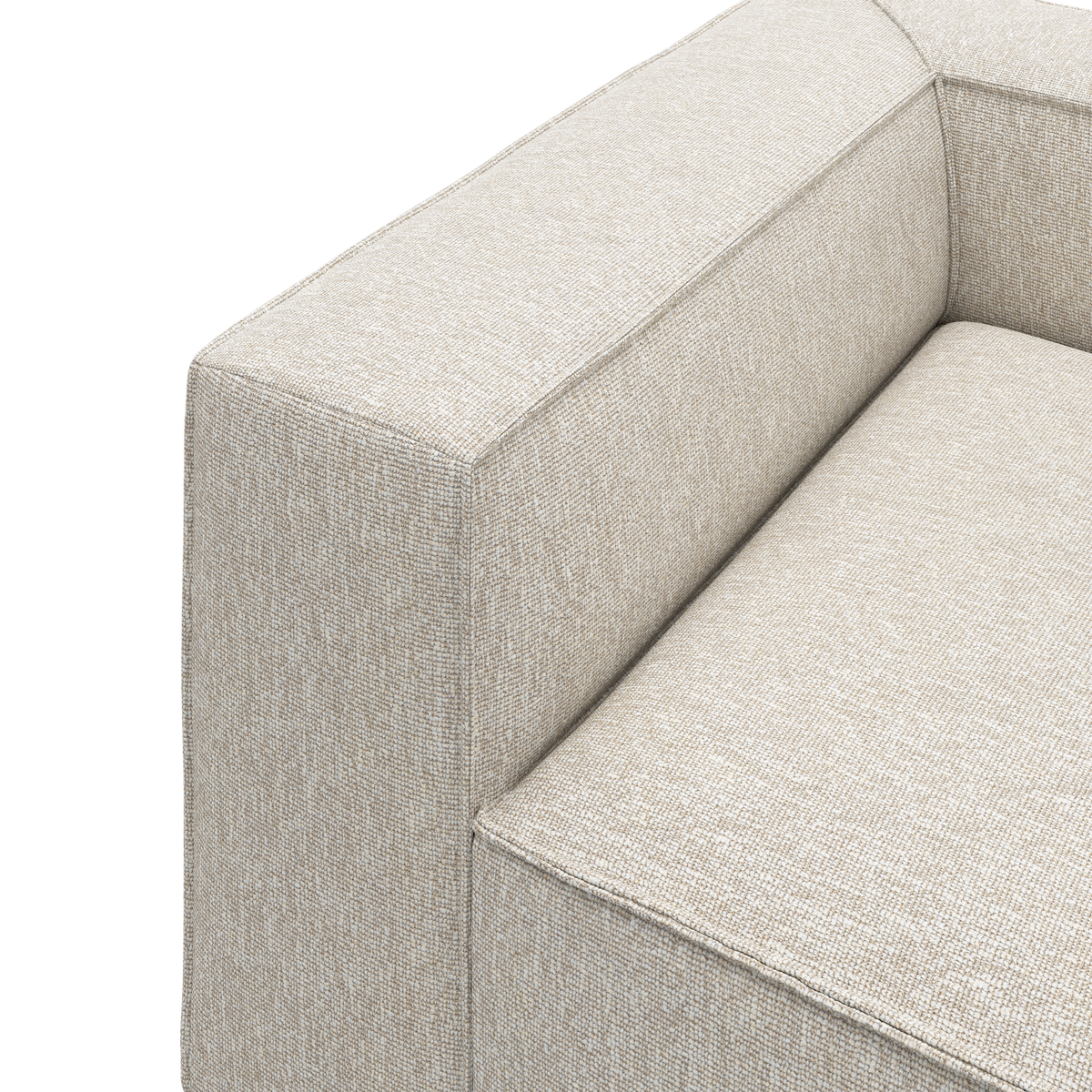 Nærbillede af beige stofsofa med kraftigt armlæn og sæde mod hvid baggrund.