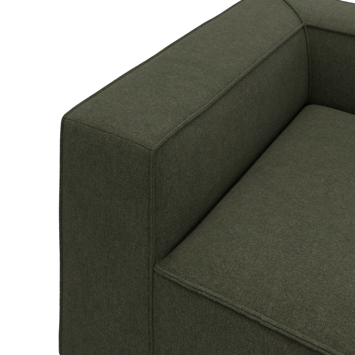 Detaljebillede af grøn stofsofa med bred armlæn og sæde.