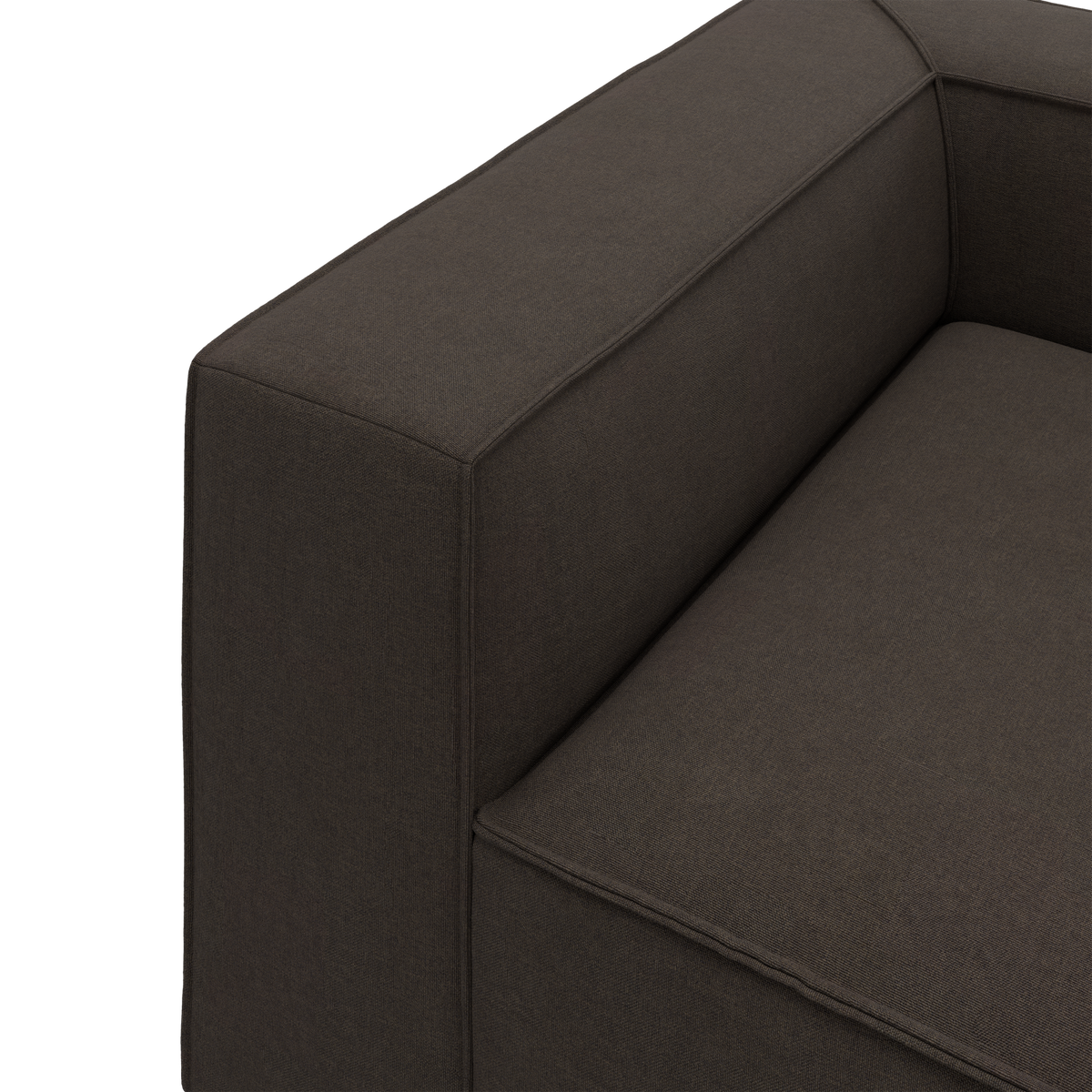Nærbillede af mørkebrun stofsofa med kantet armlæn og sæde, moderne og minimalistisk.
