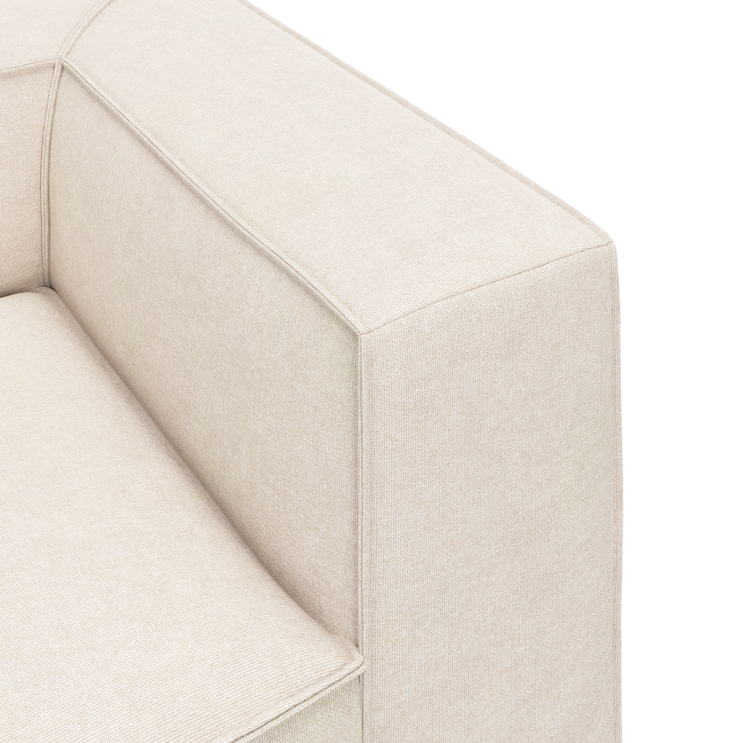 Nærbillede af hjørne og armlæn på en beige stofsofa med rene, boxede linjer.
