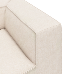 Nærbillede af hjørne og armlæn på en beige stofsofa med rene, boxede linjer.