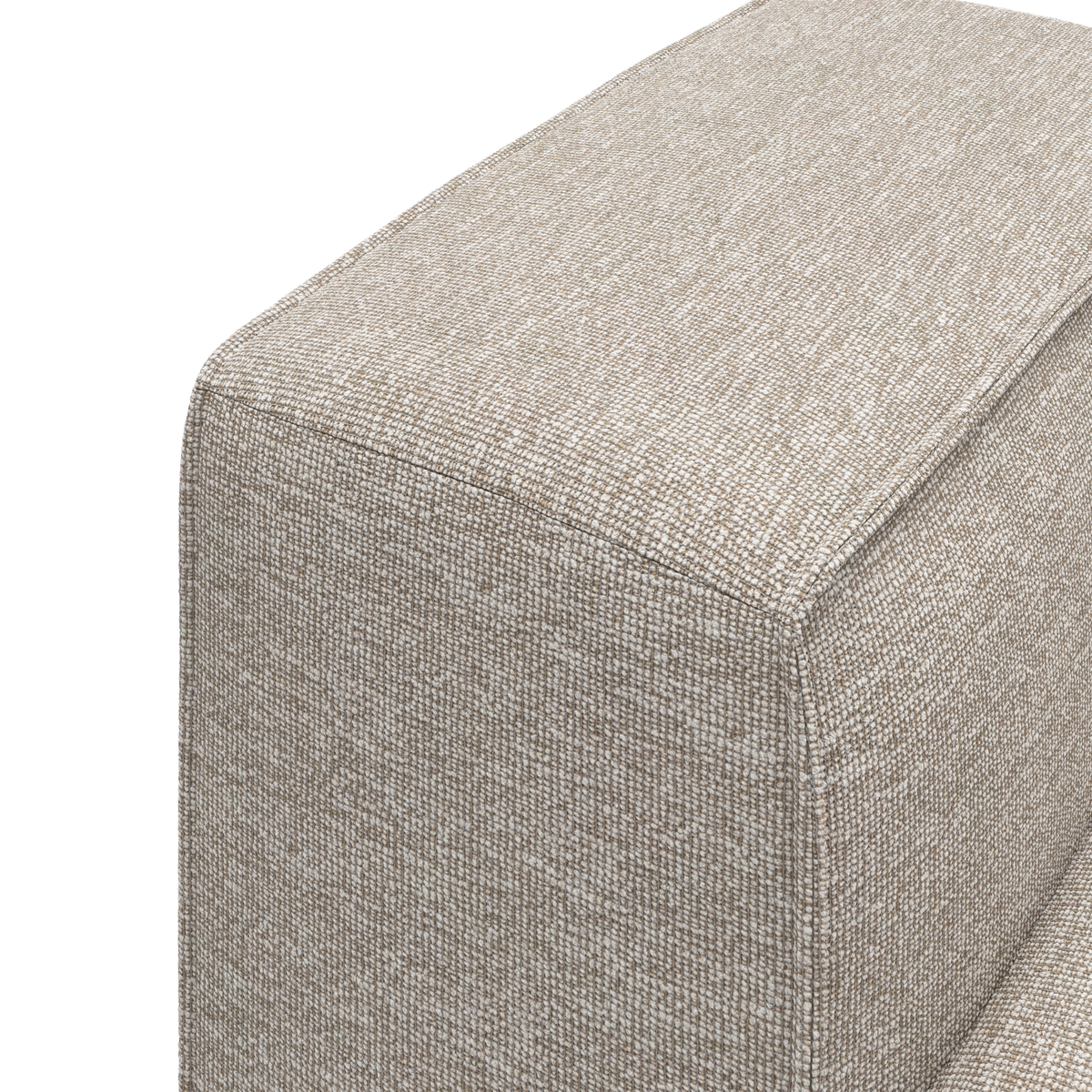 Nærbillede af hjørnet på en beige, struktureret stofsofa/ottoman med synlig pipingkant mod hvid baggrund.