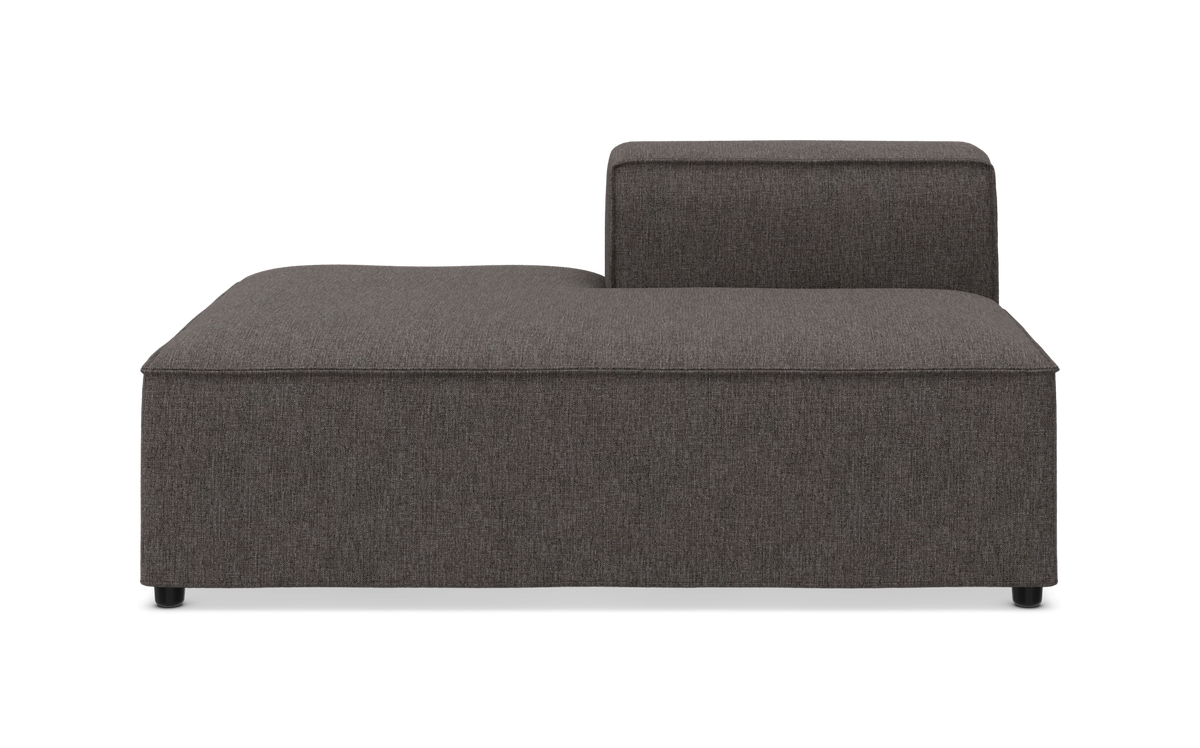 Mørkegrå modulsofa-del med lav ryg og stor L‑formet liggedel, frontvisning i studieoptagelse.