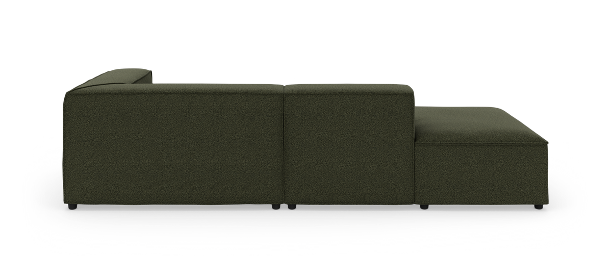 Mørkegrøn modulsofa med chaiselong set fra siden på hvid baggrund.