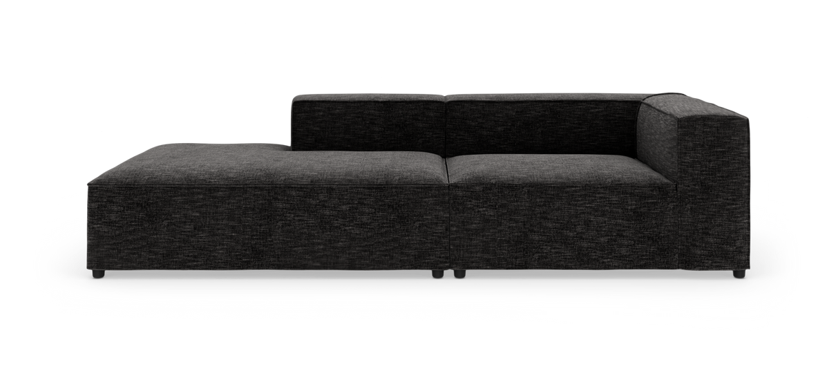 Modulsofa med chaiselong i mørkegråt stof, fotograferet lige forfra på hvid baggrund.