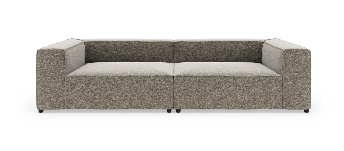 Modulsofa i grå‑beige stof med lave, brede armlæn og boxet, minimalistisk form, fotograferet lige forfra på hvid studiobaggrund.