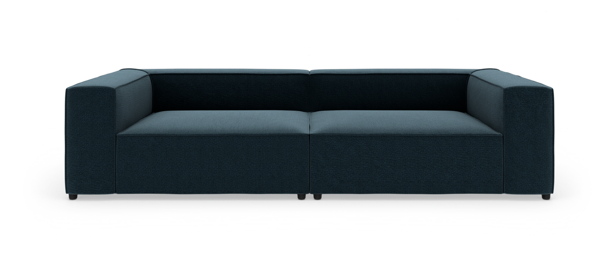Mørkeblå moderne modulsofa med brede armlæn, fotograferet lige forfra mod hvid studiebaggrund.