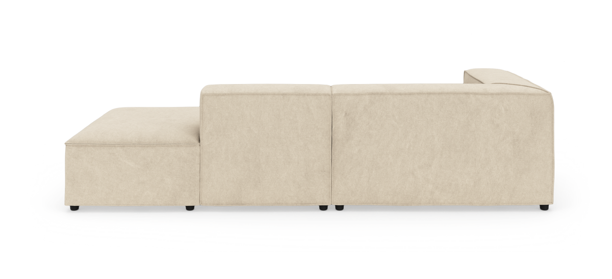 Beige modulsofa med chaiselong, set fra siden på hvid studiobaggrund.