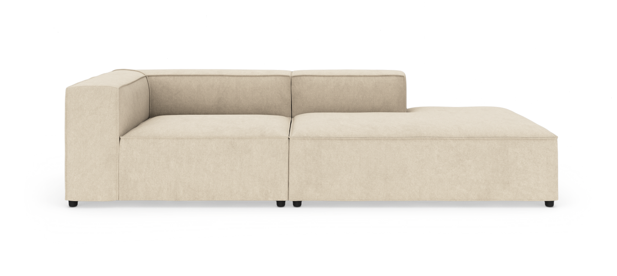 Beige modulsofa med chaiselong til højre, fotograferet forfra på hvid baggrund.