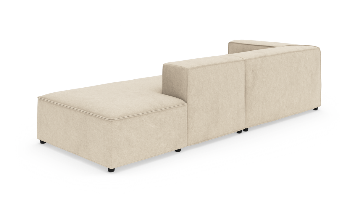 Beige modulsofa med lav ryg, vist bagfra i skrå vinkel på hvid baggrund.