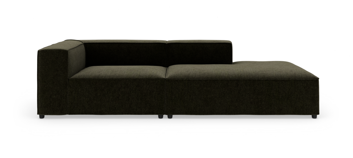 Mørkegrøn modulsofa med venstre armlæn og højre chaiselong, lav ryg og minimalistisk design, frilagt mod hvid baggrund.