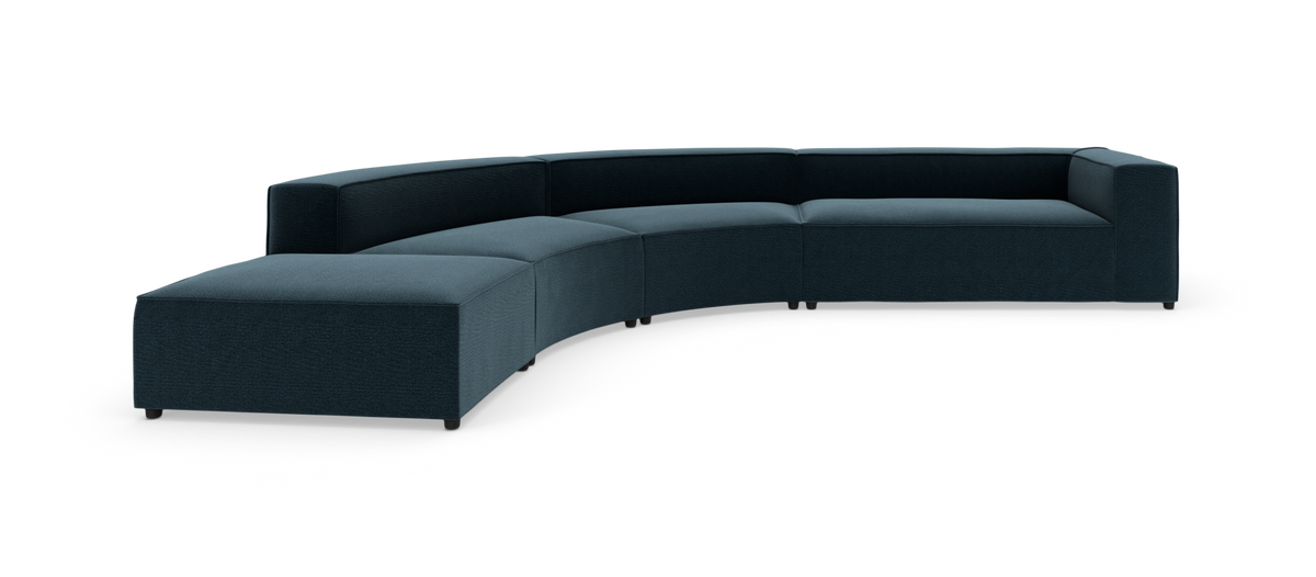 Modulær buet sofa i mørk petrolblå med lav ryg og brede armlæn på hvid baggrund.