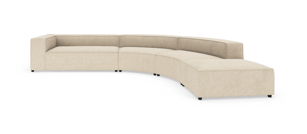 Beige, buet modulsofa med brede armlæn og afsluttende chaiselong til højre, frilagt på hvid baggrund.