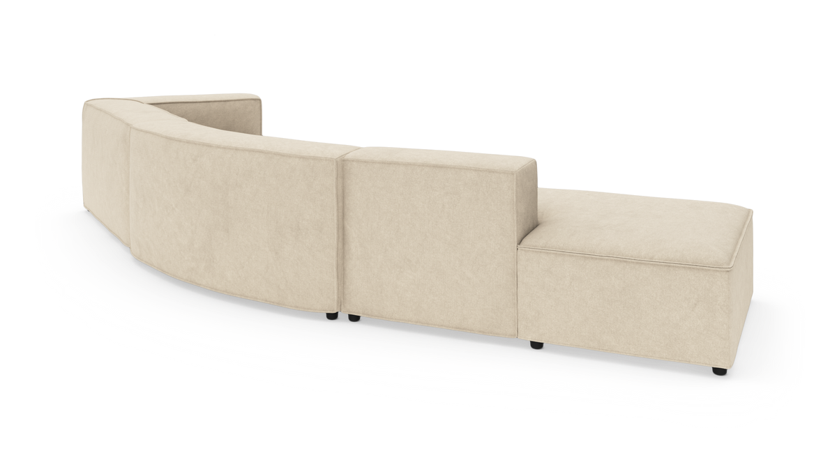 Beige modulsofa med buet ryglæn set bagfra i studie, lav profil og chaiselong i højre side.