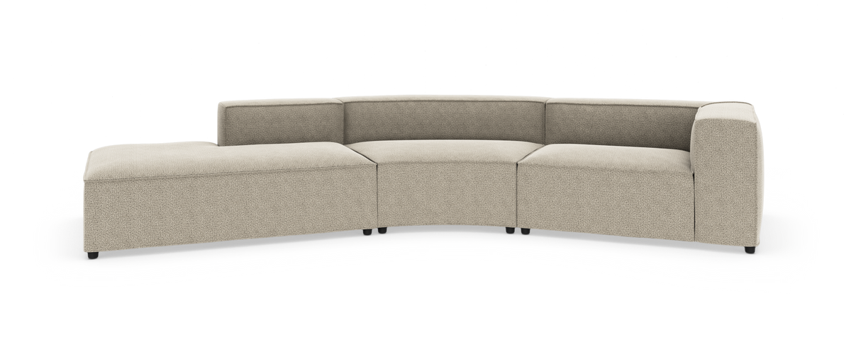 Beige modulsofa i buet L-form med chaiselong til venstre og bred armlæn til højre.