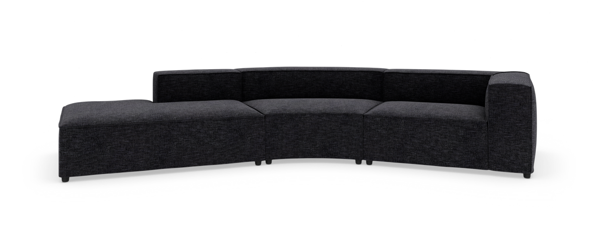 Mørkegrå modulsofa med blødt buet layout og chaiselong til venstre, fritlagt på hvid baggrund.