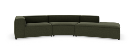 Modulsofa i mørkegrønt stof, let buet med lav ryg og chaiselong i højre side, fritstående på hvid studiebaggrund.