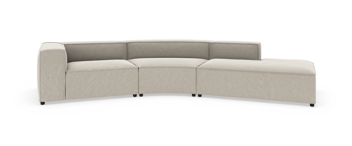 Lys beige modulsofa med buet hjørnesektion og højre chaiselong, lav ryg og kraftige sædehynder på hvid baggrund.