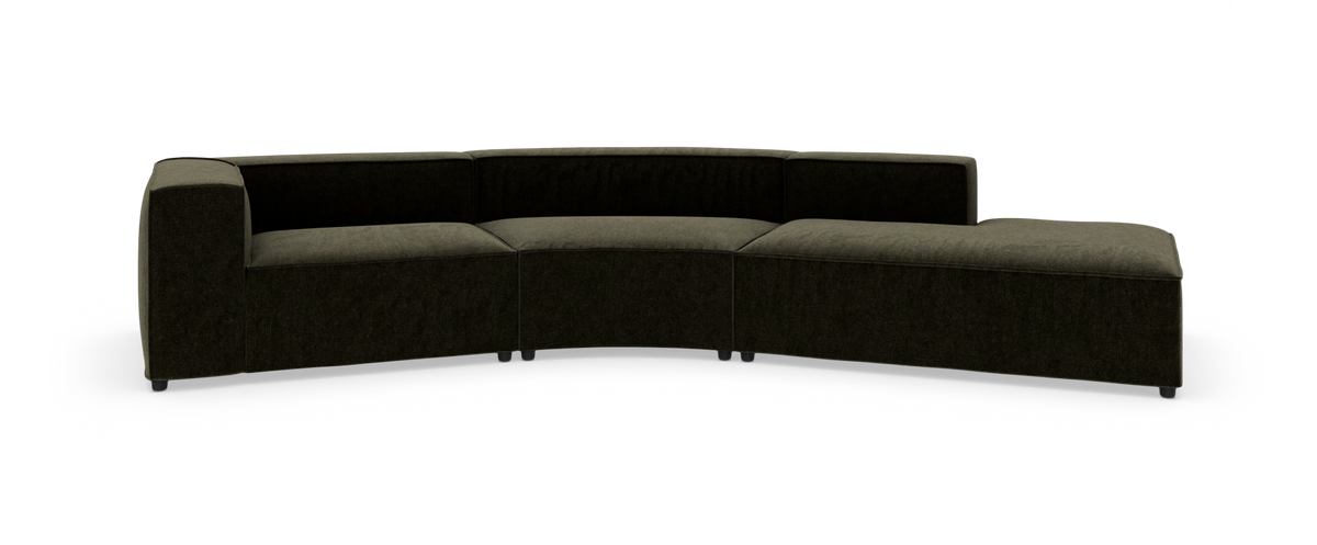Modulsofa i mørkegrønt stof, buet sektion med chaiselong, frilagt på hvid baggrund.