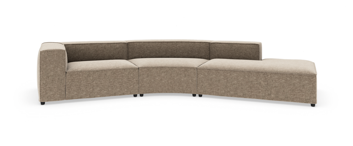 Beige modulsofa i stof med blødt buet form og chaiselong til højre, frilagt på hvid baggrund.