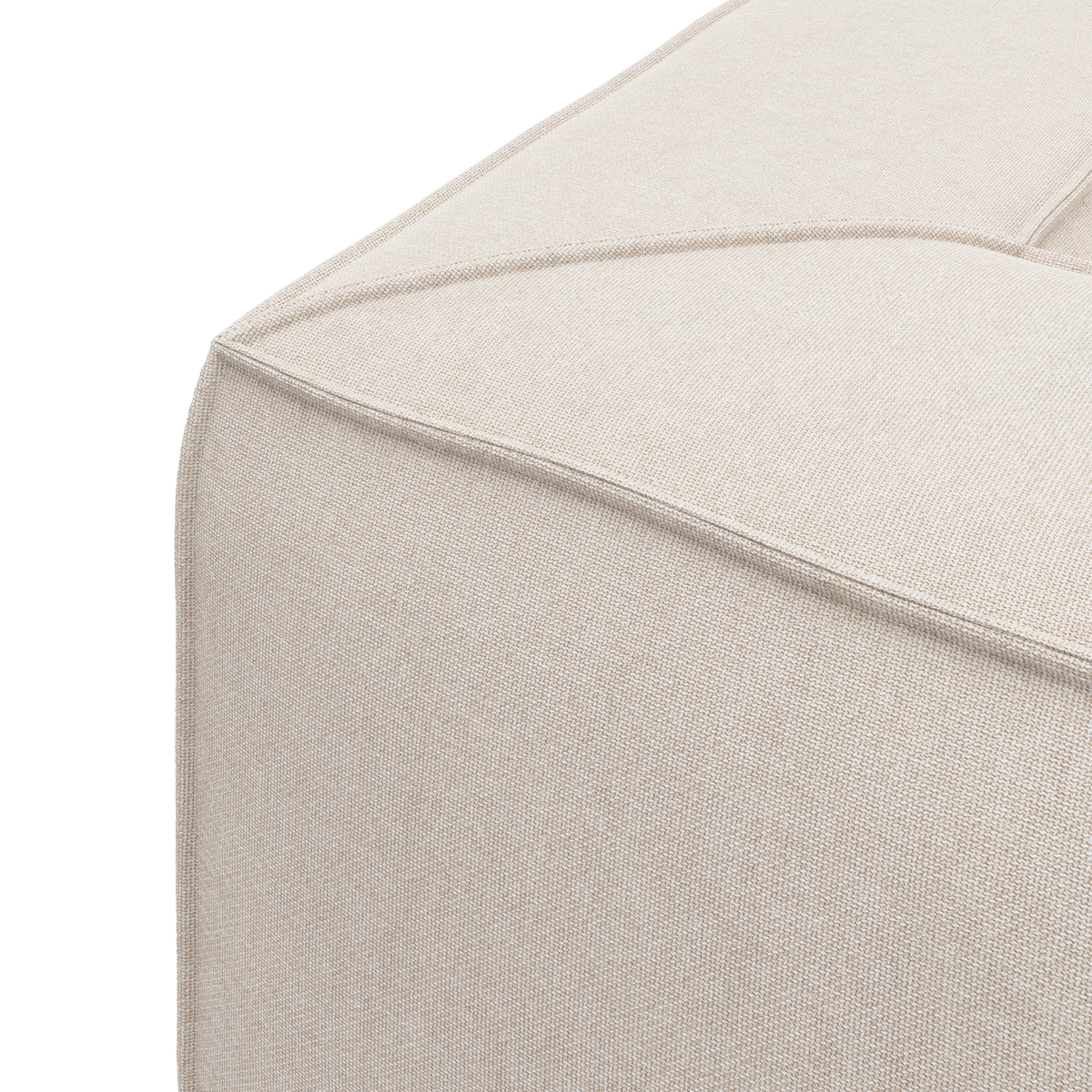 Nærbillede af hjørnet på en beige stofbeklædt puff/sofa med markerede syninger mod hvid baggrund.
