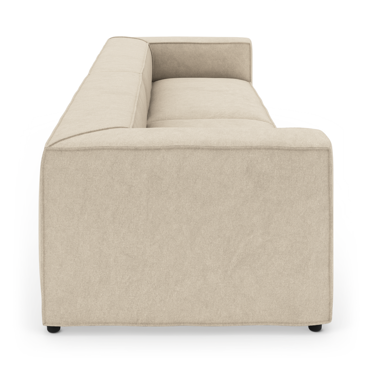Beige modulsofa set fra siden med tykke hynder og rene linjer på hvid studiobaggrund.