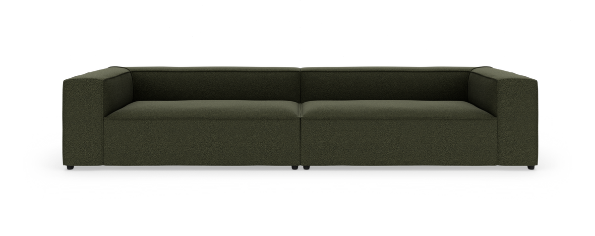 Modulsofa i mørkegrønt tekstil med brede armlæn, fotograferet lige forfra i studie på hvid baggrund.