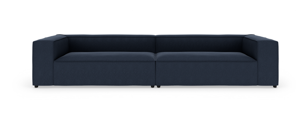 Mørkeblå modulsofa med lave armlæn, vist i studie forfra.